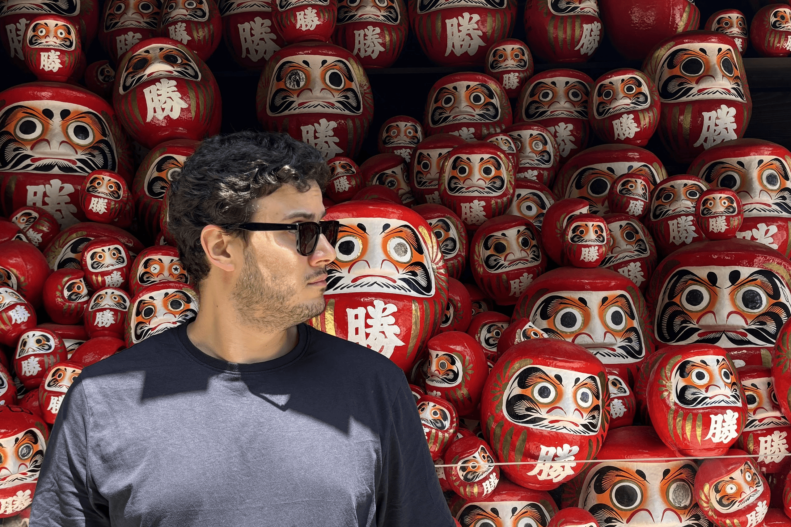 Photo of Domingo Widen standing in front of Daruma Dolls (だるま)